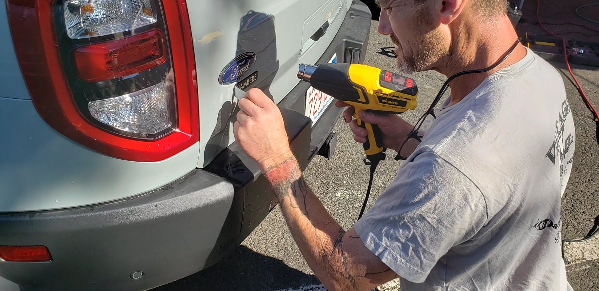 Image of detailer removing dealer sticker from car by John Goreham