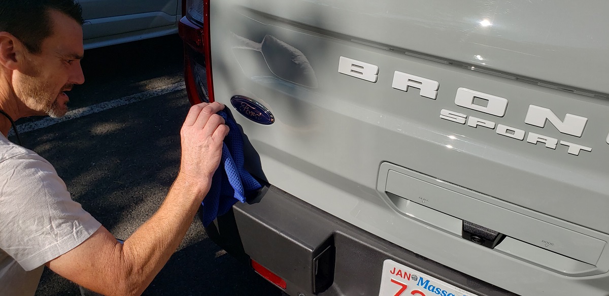 Image of detailer removing dealer sticker from car by John Goreham