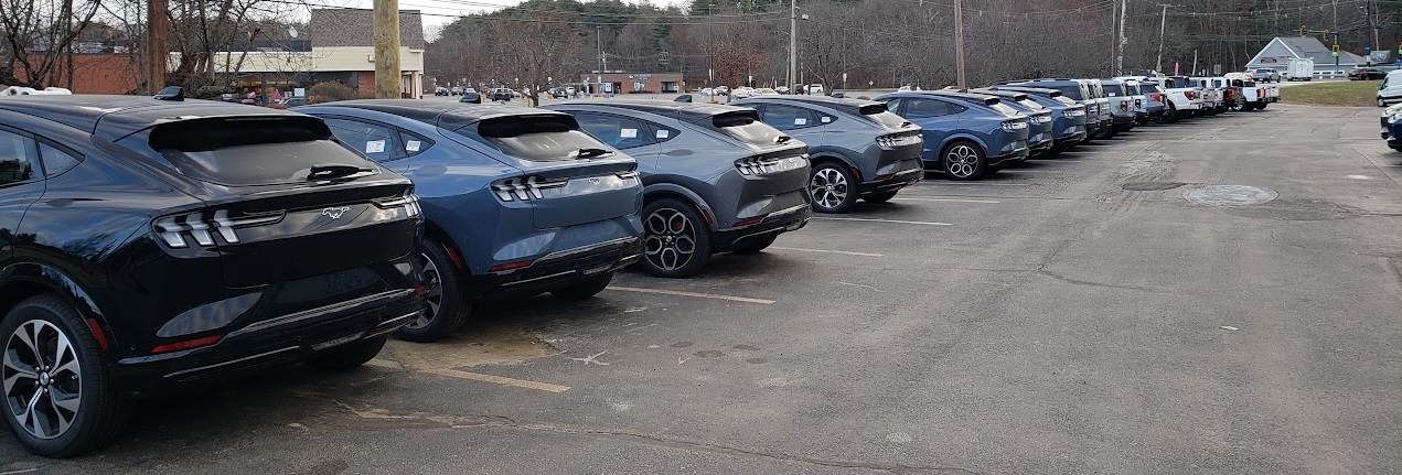 Image of 2024 Ford Mustang Mach-E cars in a line at dealership by John Goreham. 