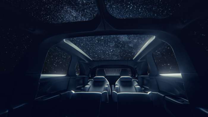 View of the Lucid Gravity's interior as seen from the front seats. The vehicle's long glass roof is visible, as is its reclining second row seats.