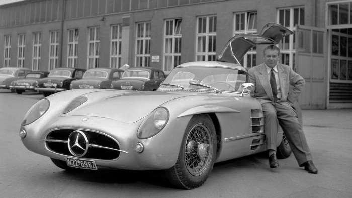 Rudolf Uhlenhaut sits on the door sill of one of the 300SLR Uhlenhaut Coupes outside the Mercedes factory.