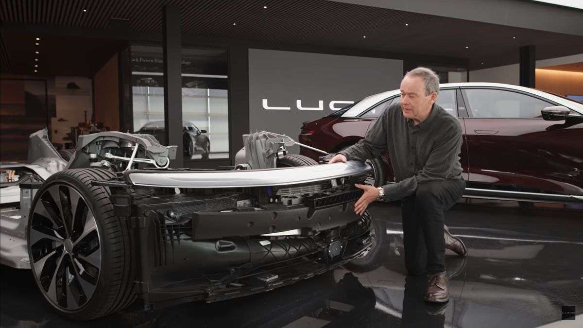 Image of Lucid CEO Peter Rawlinson crouched beside a disassembled Lucid Air front end module showing the placement of its camera and sensors.