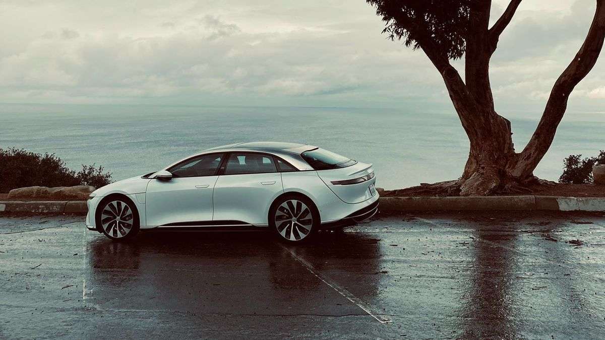 Image of a white Lucid Air parked on a Californian hilltop on a rainy day.