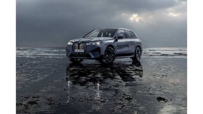 Image showing a dark blue BMW iX M60 parked on a beach beneath an overcast sky.