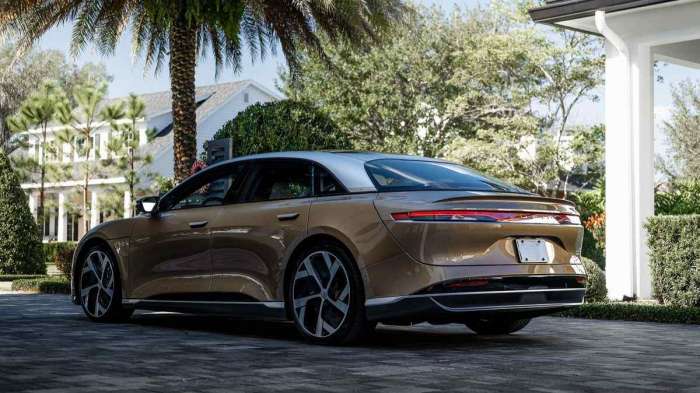 A gold Lucid Air Dream Edition is pictured under palm trees.