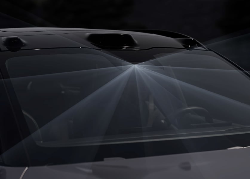 A close-up, high-angle view of the windshield and roofline of a Nio car, showing light beams radiating from the front-facing camera area to visualize its autonomous sensor technology.