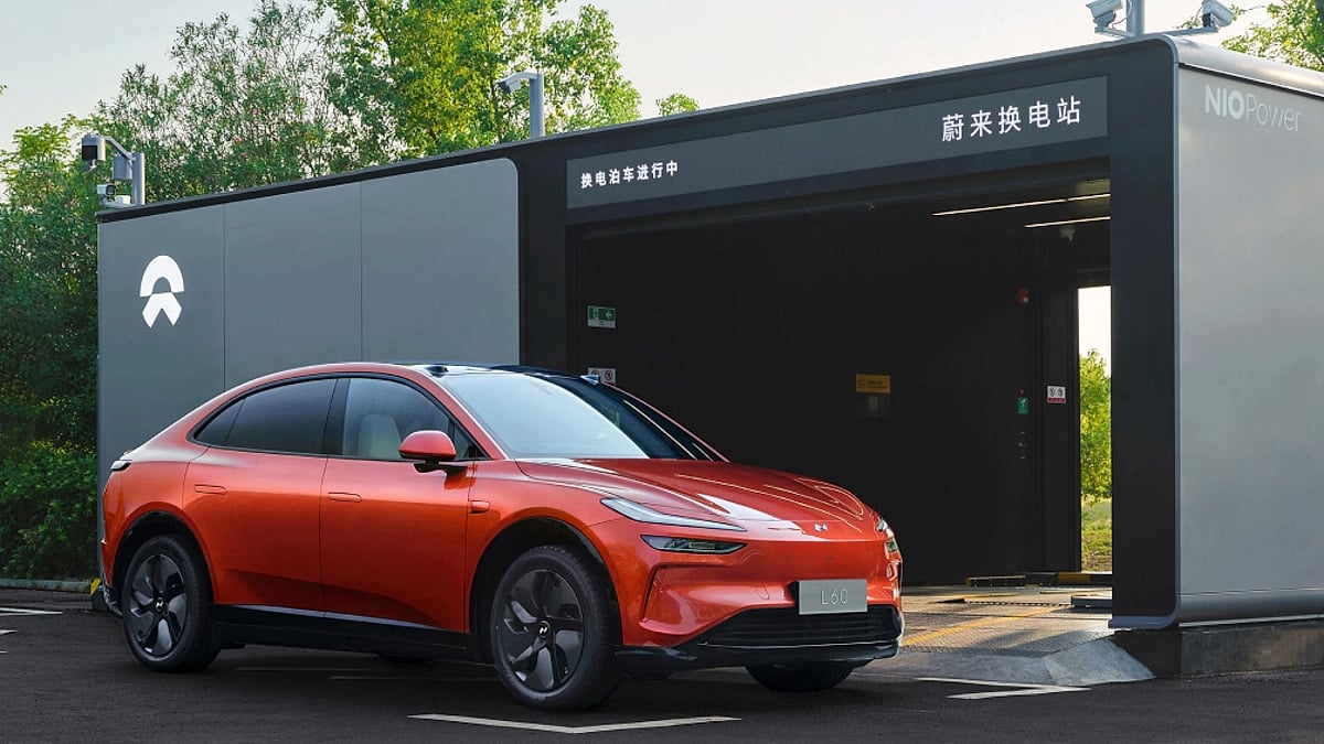 Onvo L60 electric SUV parked in front of an NIO Power battery swap station.