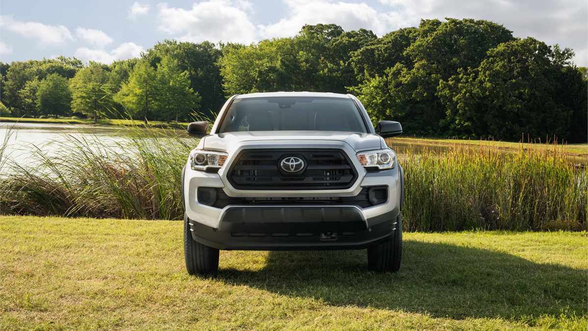 Silver Toyota Tacoma parked by a pond, side profile of midsize pickup truck