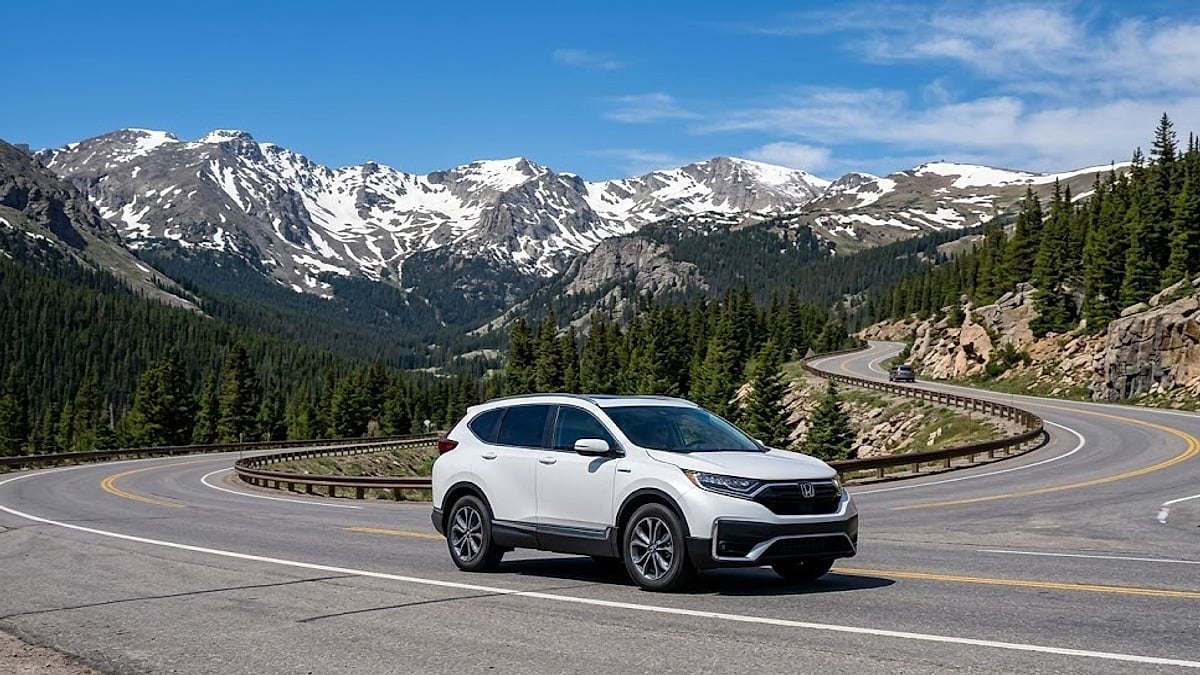 2020 Honda CR-V Hybrid navigating a high-altitude mountain highway curve in the snow-capped Rocky Mountains of Colorado
