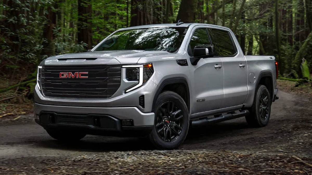 Silver GMC pickup truck parked on a dirt road in a forested area.