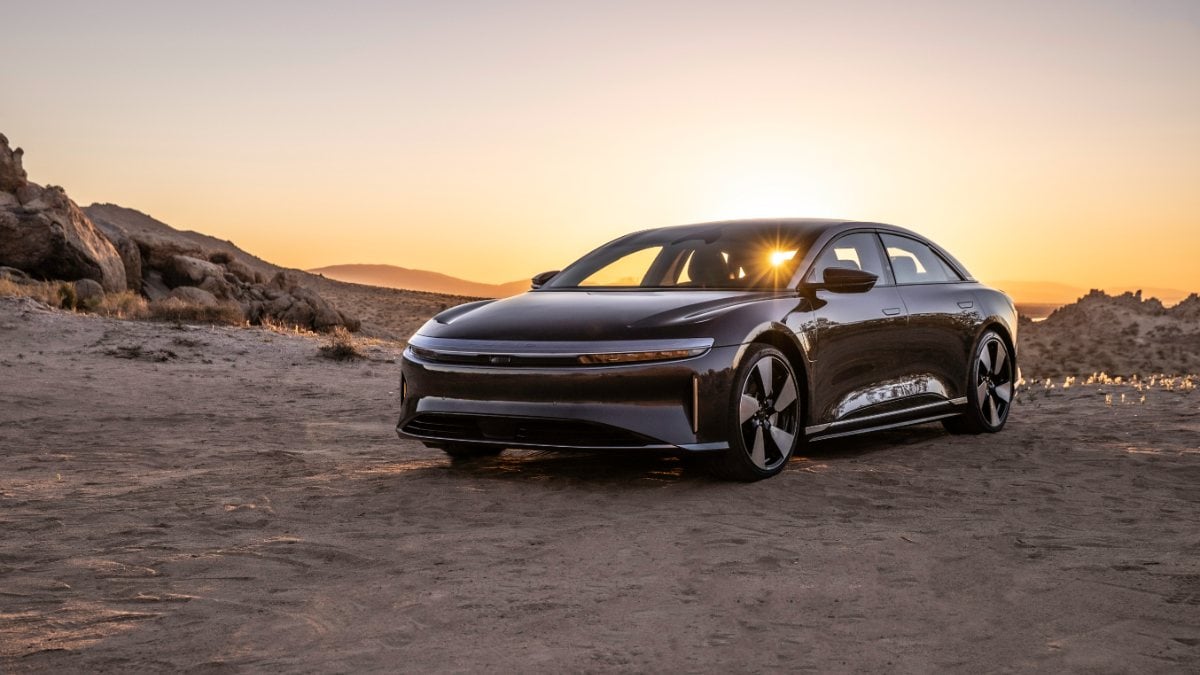 Lucid Air Touring luxury electric sedan in black parked in a desert landscape at sunset with warm lighting.