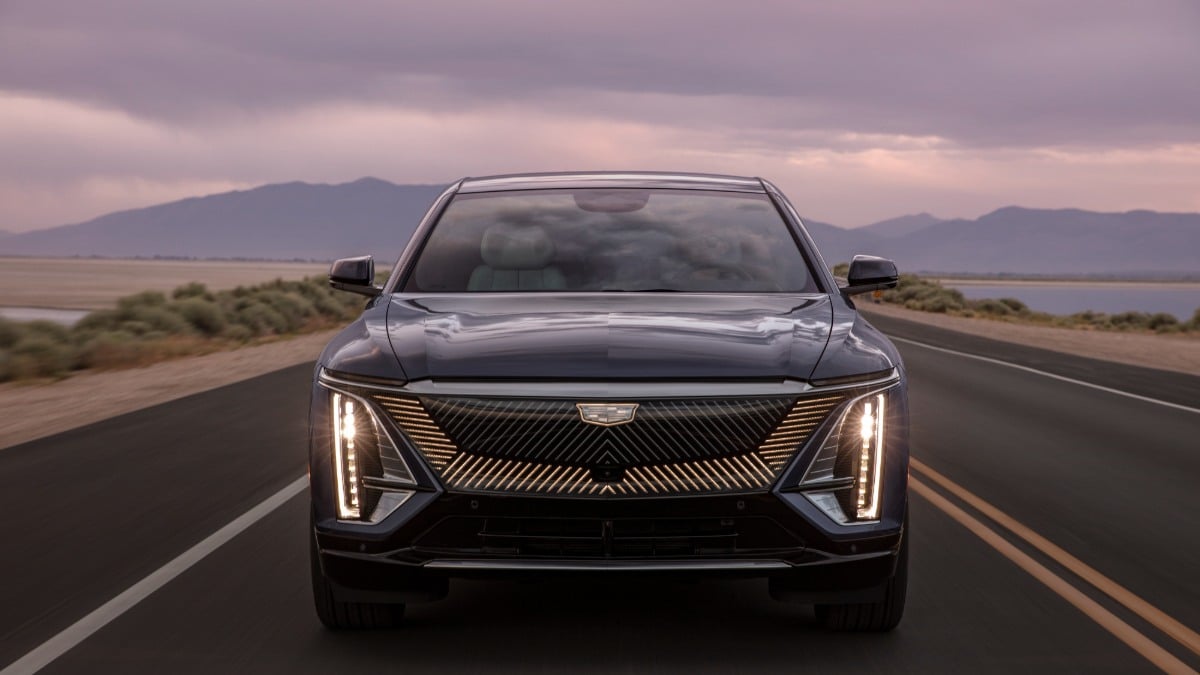 Front view of a 2023 Cadillac Lyriq electric SUV on an open highway, featuring the illuminated Cadillac grille and signature LED lighting.