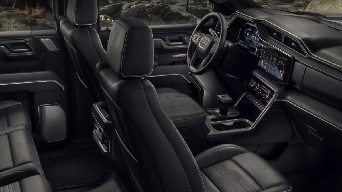 Interior of a 2023 GMC Sierra 1500 with a black leather finish. The dashboard features a digital display and controls, exuding a high-tech feel.