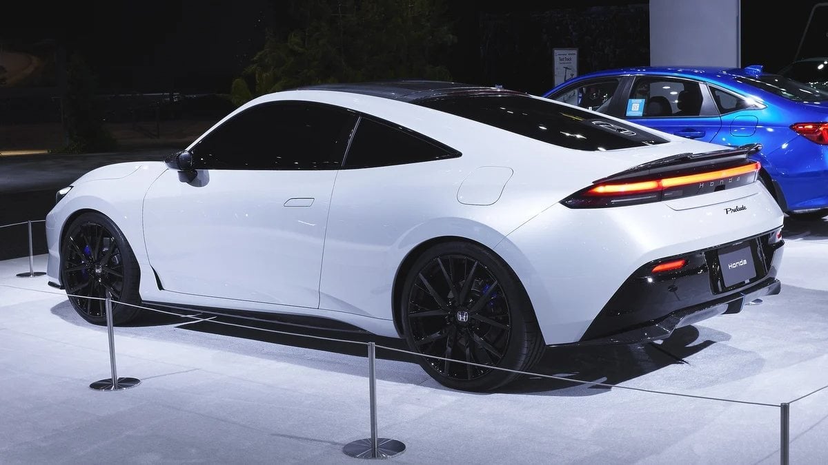 The rear three-quarter view of the white 2026 Honda Prelude concept, showcasing its sleek taillight design and aerodynamic profile at an auto show.