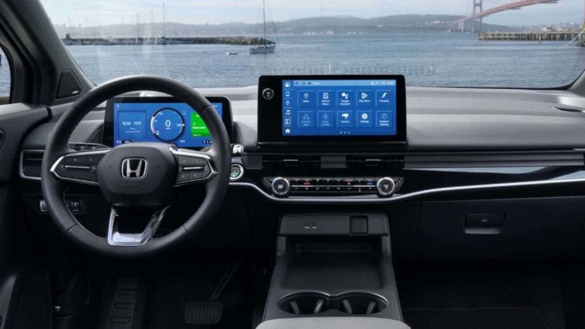 Honda Prologue interior with a modern dashboard displaying two digital screens. Through the windshield, a scenic view of a bay and distant bridge is visible.