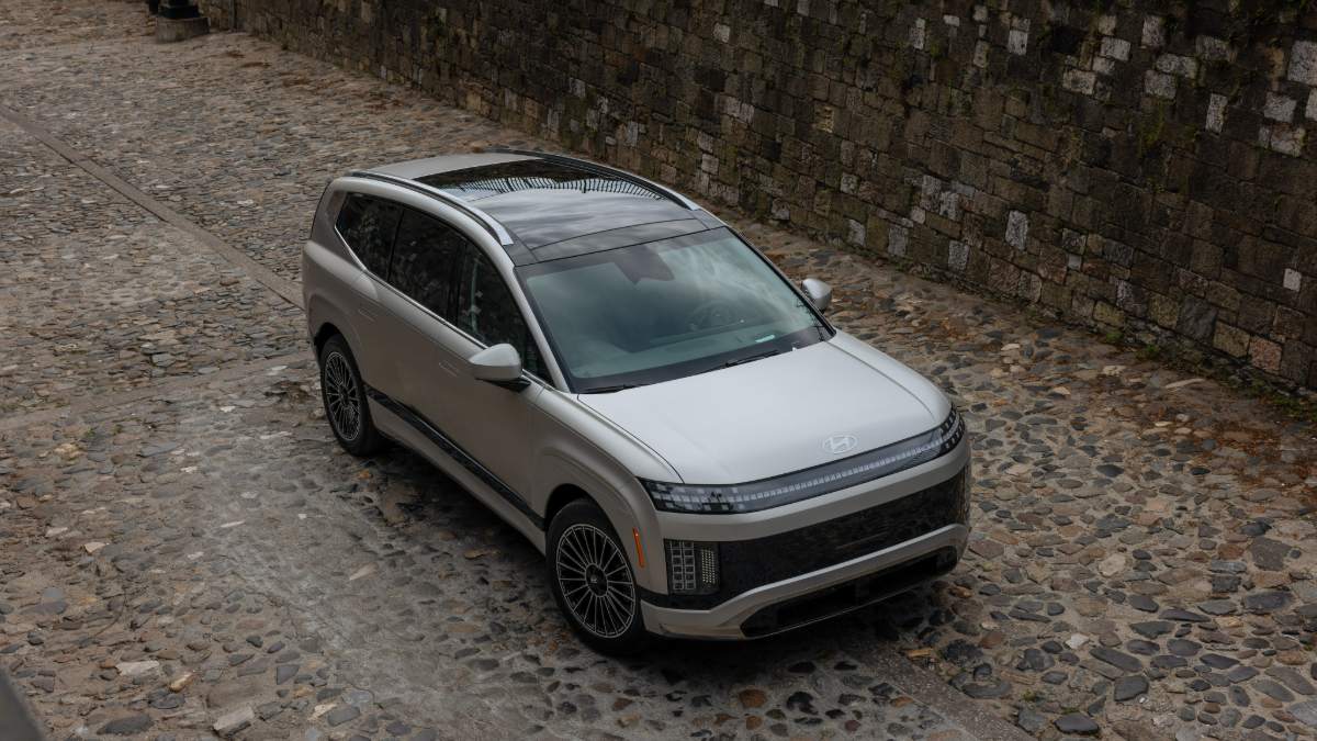 2024 Hyundai Ioniq 9 in silver, photographed from above on cobblestone street, featuring distinctive streamlined design, panoramic glass roof, and multi-spoke wheels.