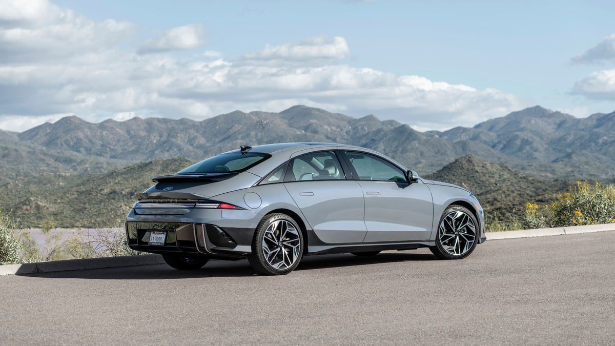 Gray 2024 Hyundai Ioniq 6 Limited shown from the rear three-quarter angle beside a mountain landscape.