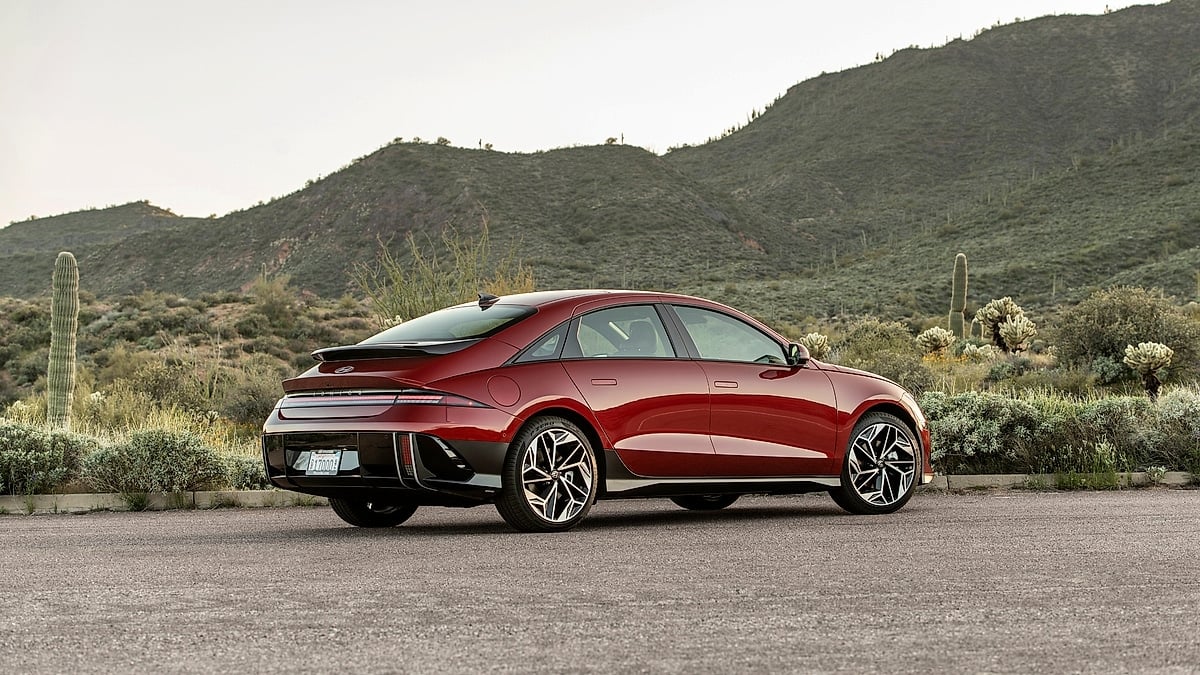 Red 2024 Hyundai Ioniq 6 Limited parked in a desert setting in a rear three-quarter view.