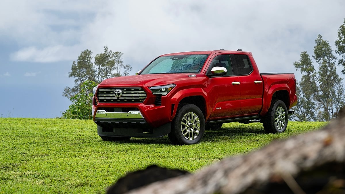 Red 2024 Toyota Tacoma Limited parked on green grass in a front three-quarter view.