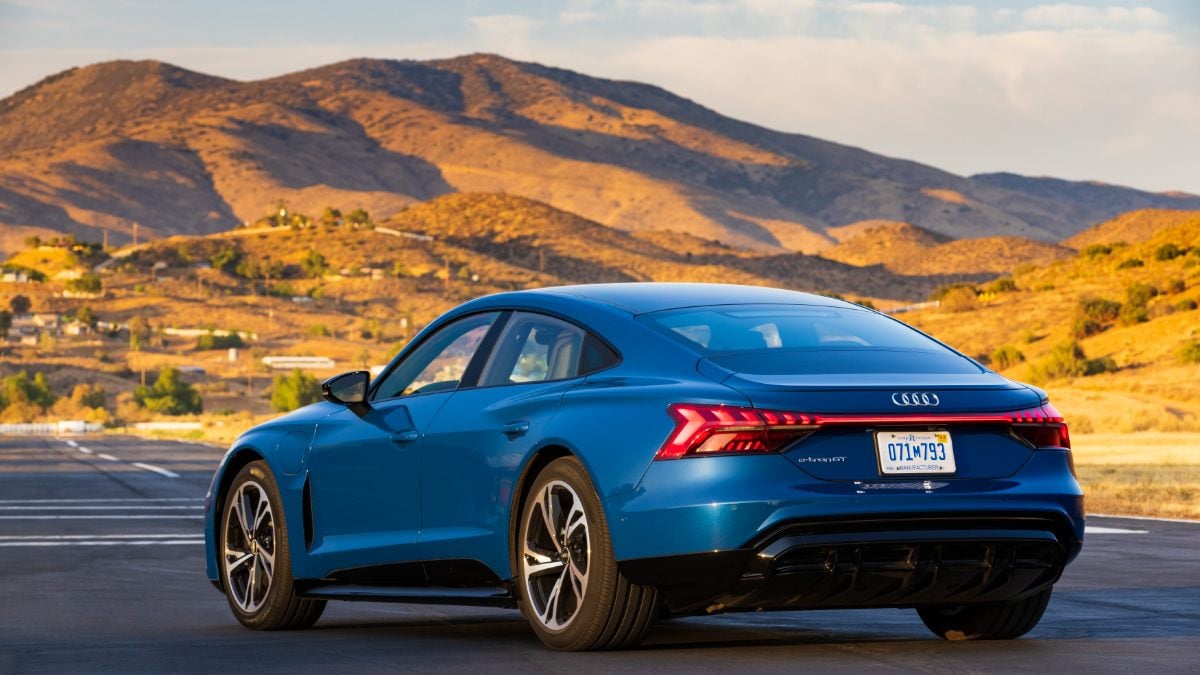 Blue Audi e-tron GT electric sedan parked against backdrop of golden mountainous landscape