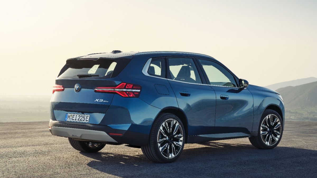 Blue BMW X3 30e electric SUV parked on rocky terrain with misty mountain backdrop, sleek design with angular LED taillights