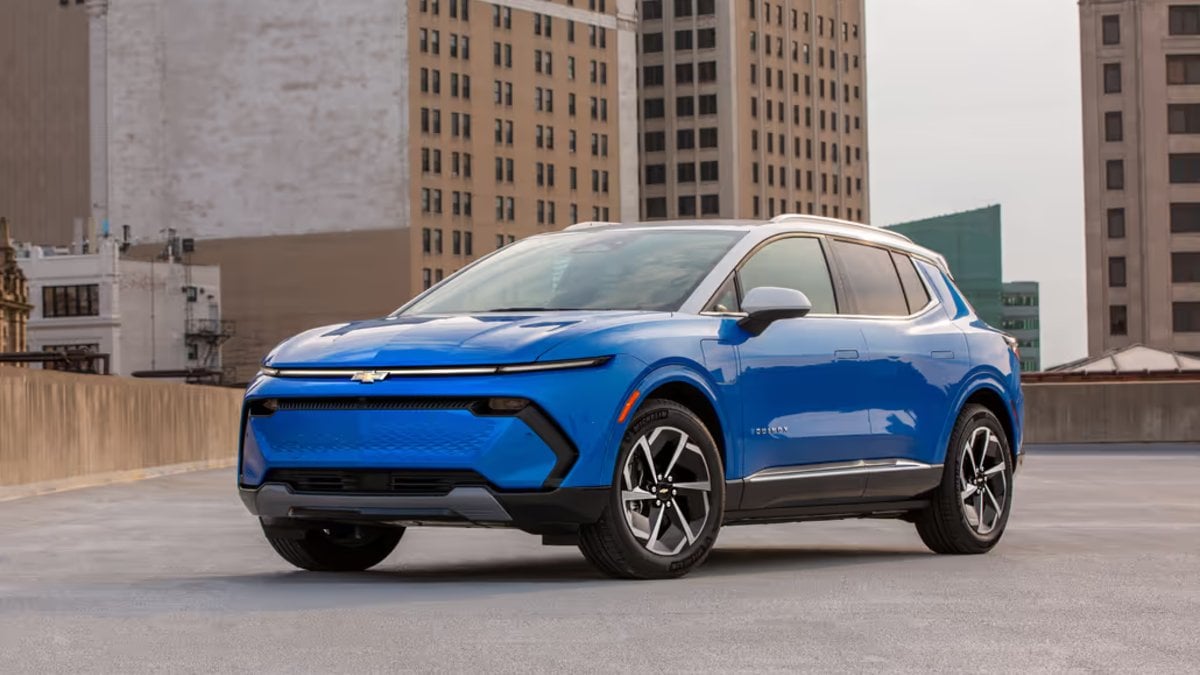 Blue SUV parked on a rooftop with city buildings in the background.