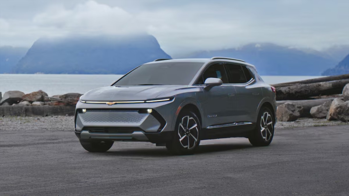 Gray 2025 Chevrolet Equinox EV SUV parked on rocky terrain with misty mountain backdrop