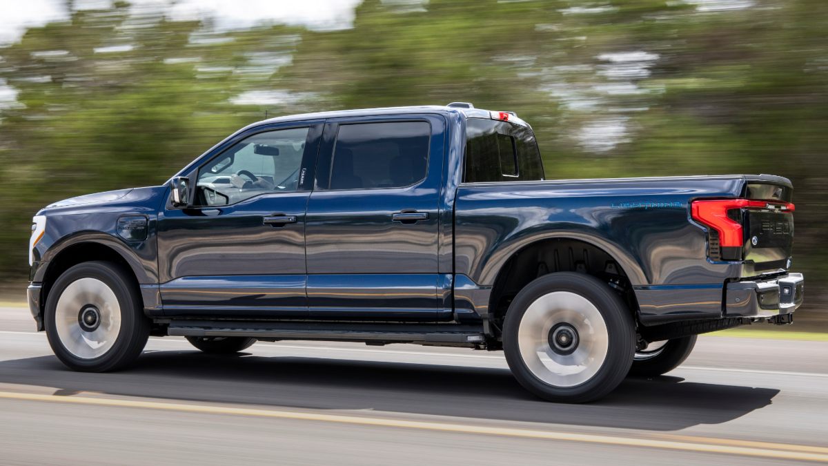 Navy blue Ford F-150 pickup truck driving on road with motion-blurred wheels