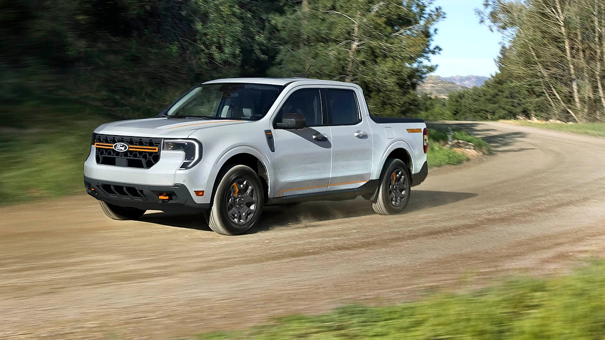 White 2025 Ford Maverick compact pickup driving on a dirt road, front three-quarter view