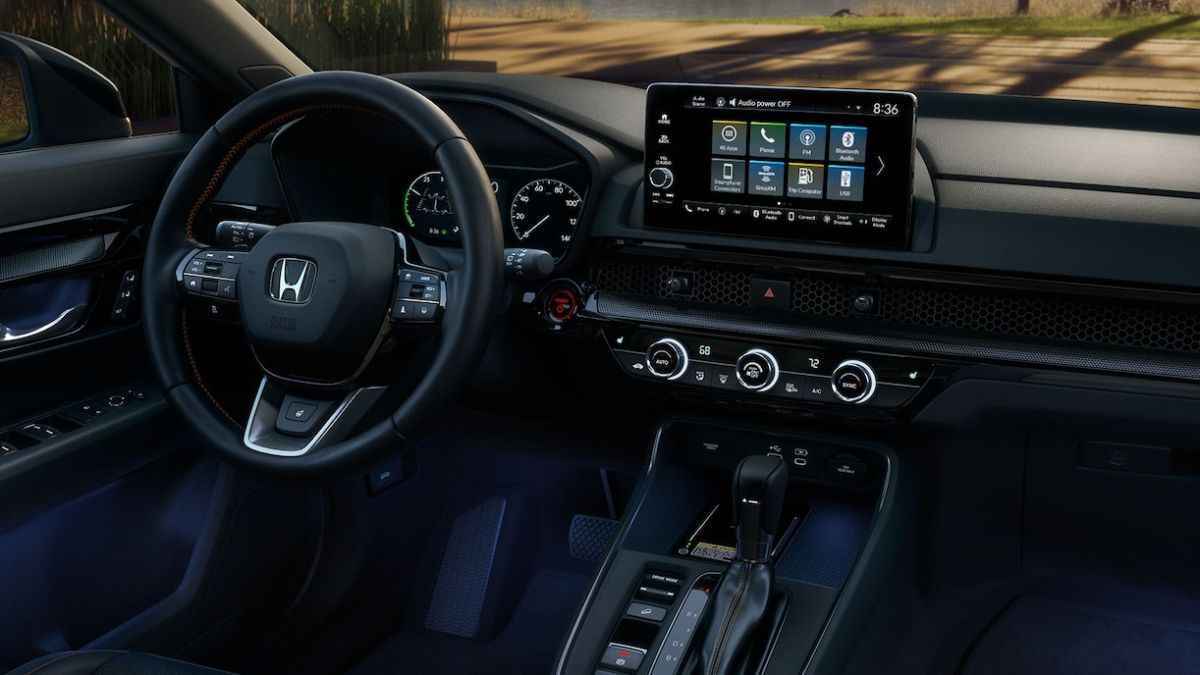 Honda CR-V interior featuring a sleek dashboard with a touchscreen display showing apps, a steering wheel with controls, and a gear shift lever.