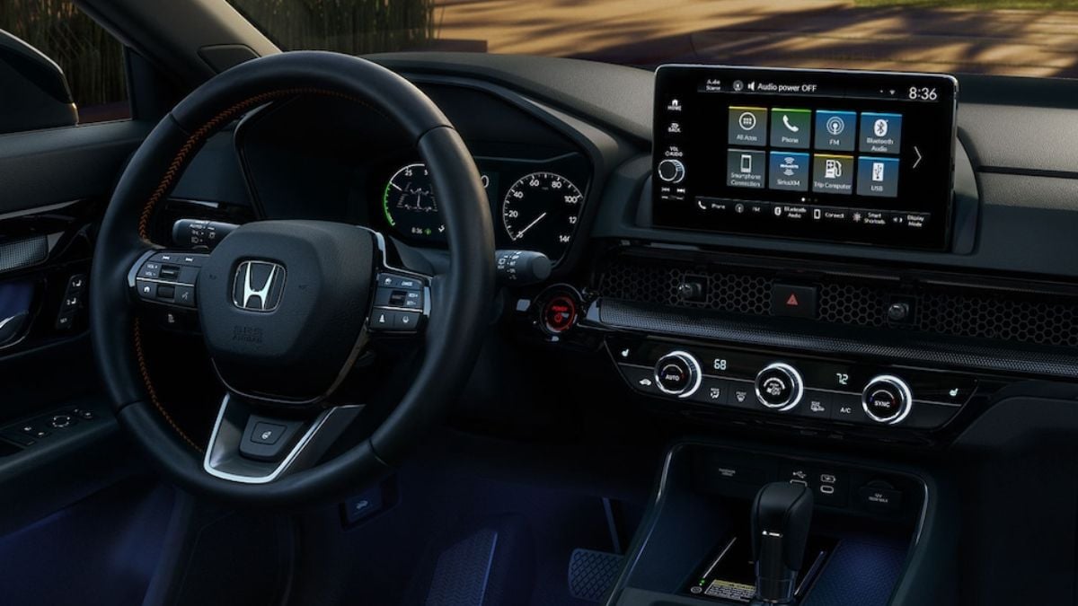 The interior of a 2025 Honda CR-V featuring a steering wheel with controls, a digital dashboard displaying gauges, and a touchscreen infotainment system.