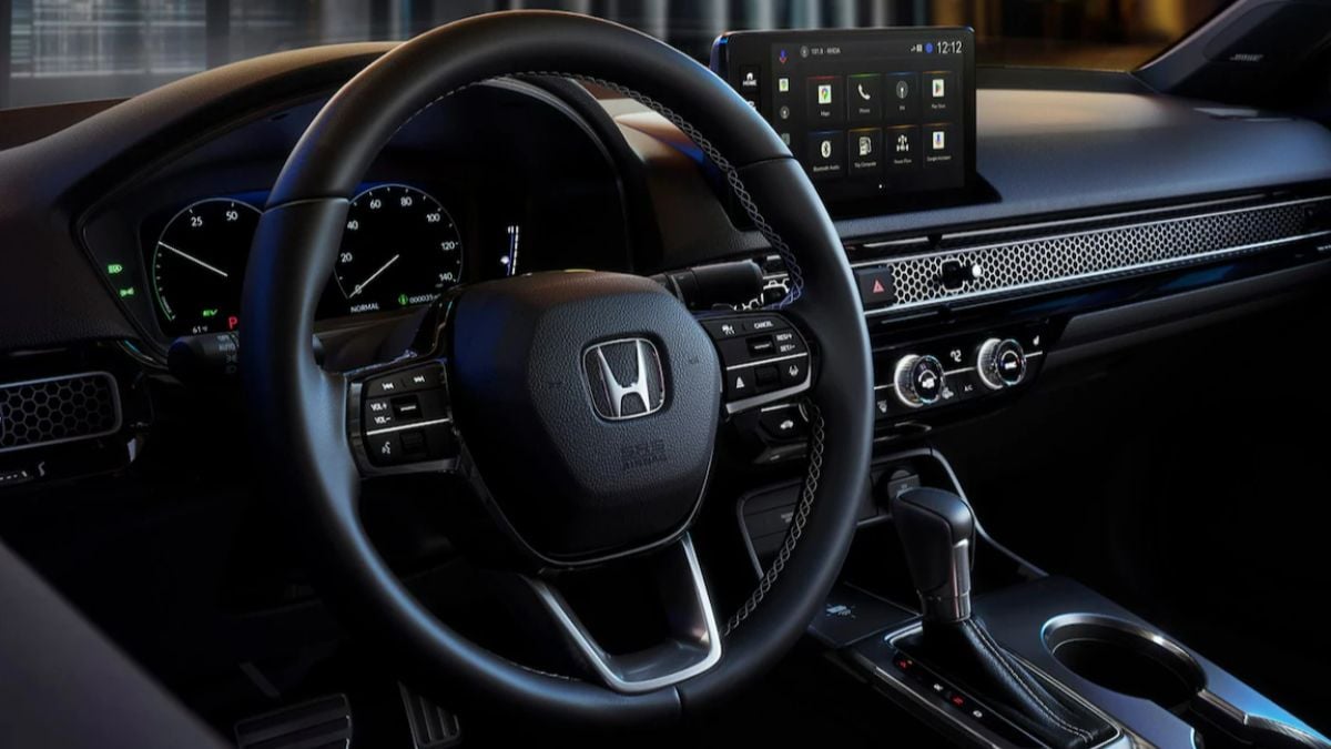 A 2025 Honda Civic interior with a black steering wheel featuring a Honda logo, digital dashboard, and infotainment screen displaying apps.