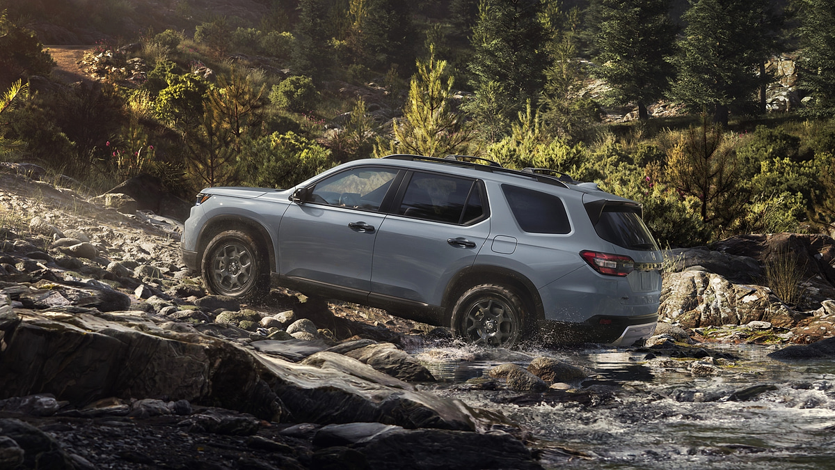 2025 Honda Pilot Black Edition SUV parked on a rocky mountain overlook with snow capped peaks behind it