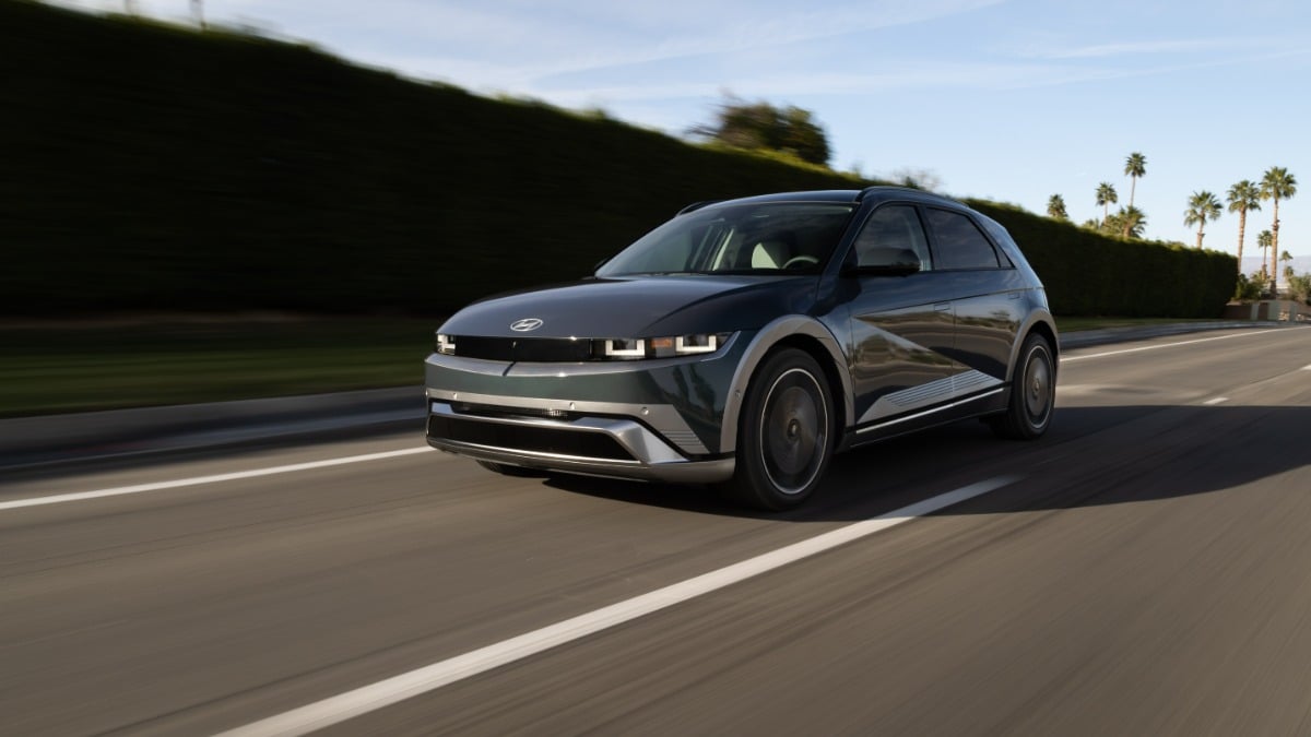 Green 2025 Hyundai Ioniq 5 electric SUV driving on a road with palm trees in the background.