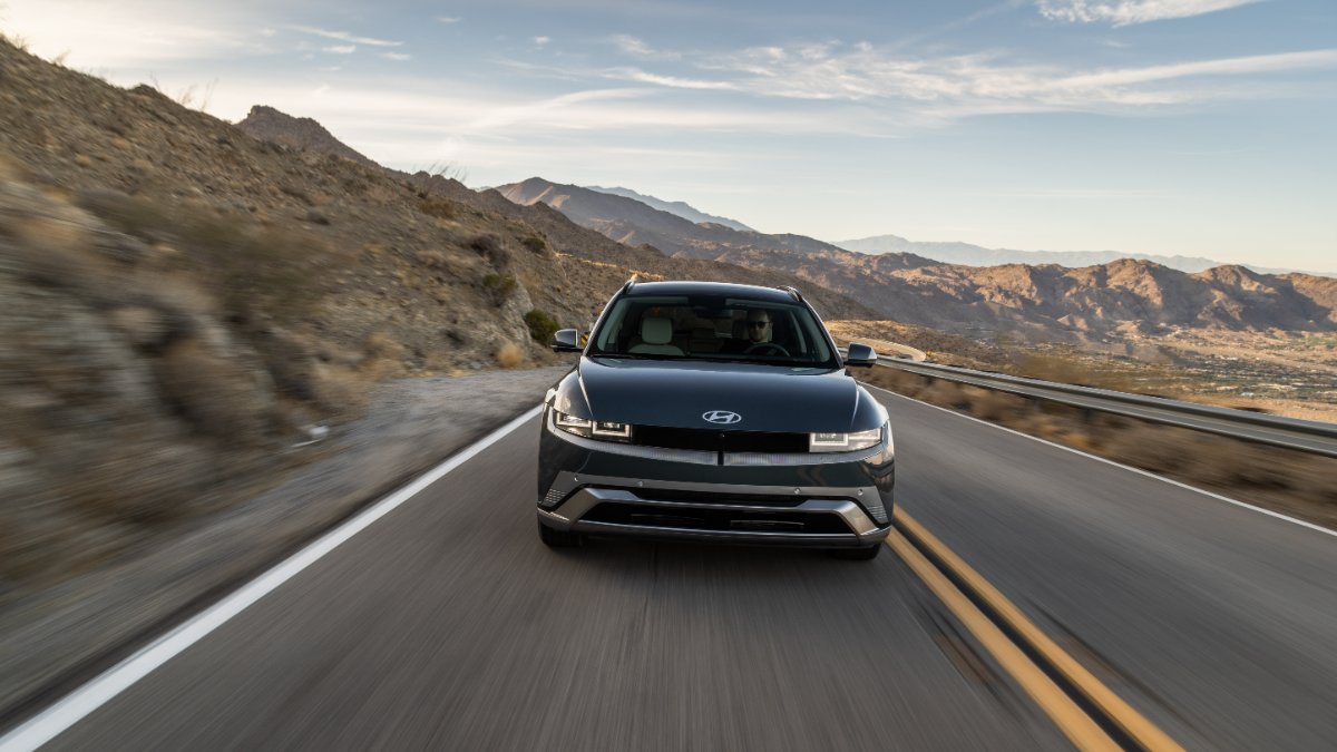 Dark gray Hyundai Ioniq 5 driving on mountain road with desert hills in background