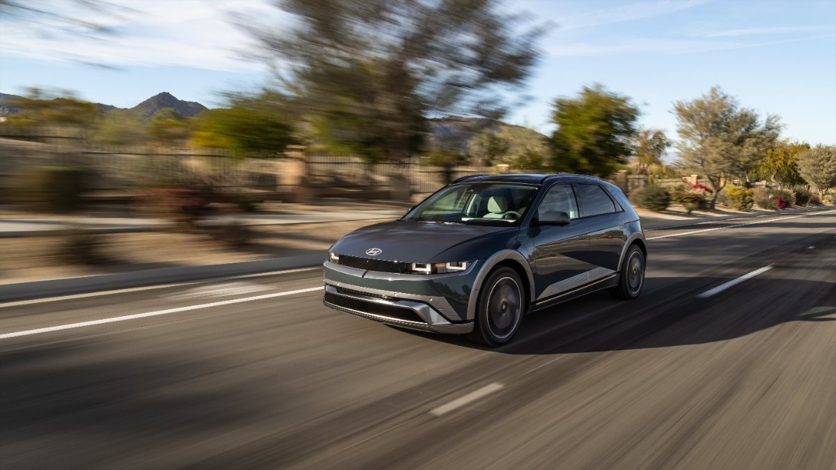 Dark blue Hyundai Ioniq 5 electric SUV driving on mountain road with blurred landscape background