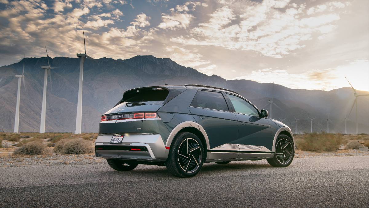 2025 Hyundai Ioniq 5, blue, rear three-quarter view, showcasing distinctive taillights and wind turbines in the background.