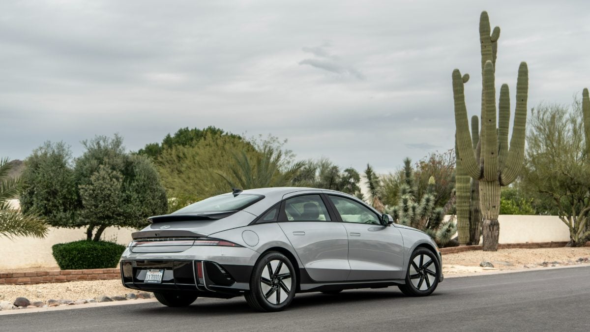 Silver sedan parked on a road, surrounded by desert vegetation and large cacti.