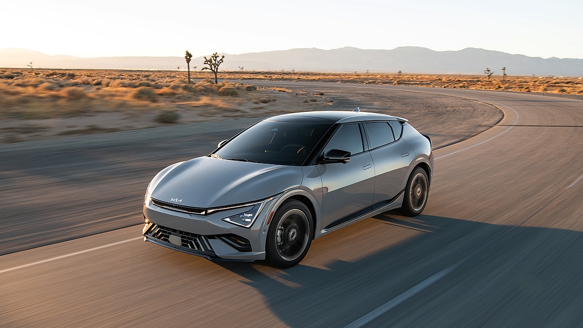 2025 Kia EV6 electric vehicle driving quickly along a desert road at sunset