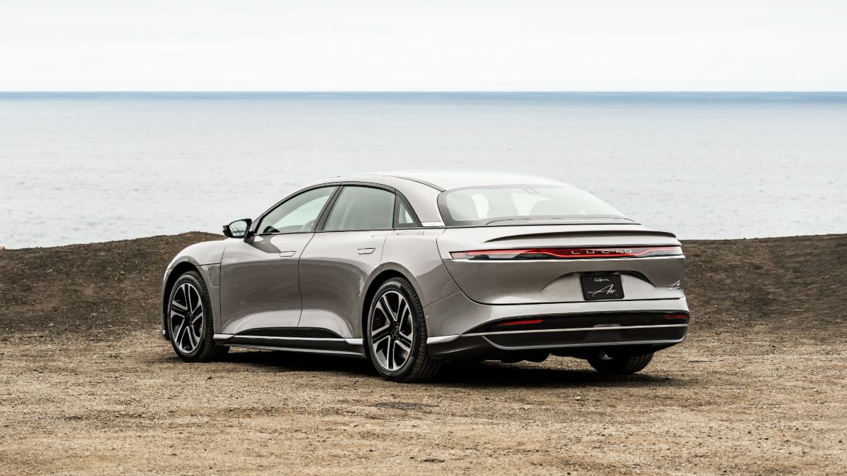 2025 Lucid Air electric sedan rear three-quarter view highlighting full-width taillight design by the ocean