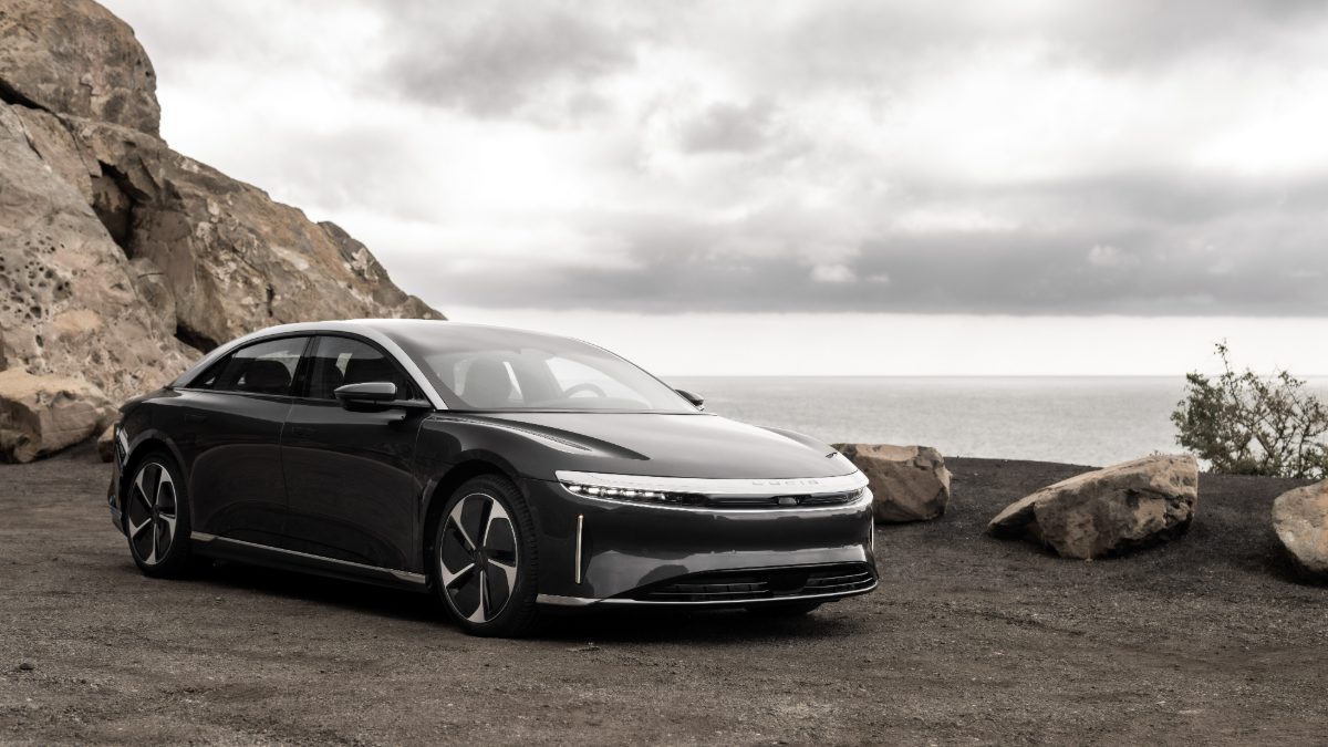 Lucid Air electric sedan parked on coastal cliff against cloudy sky