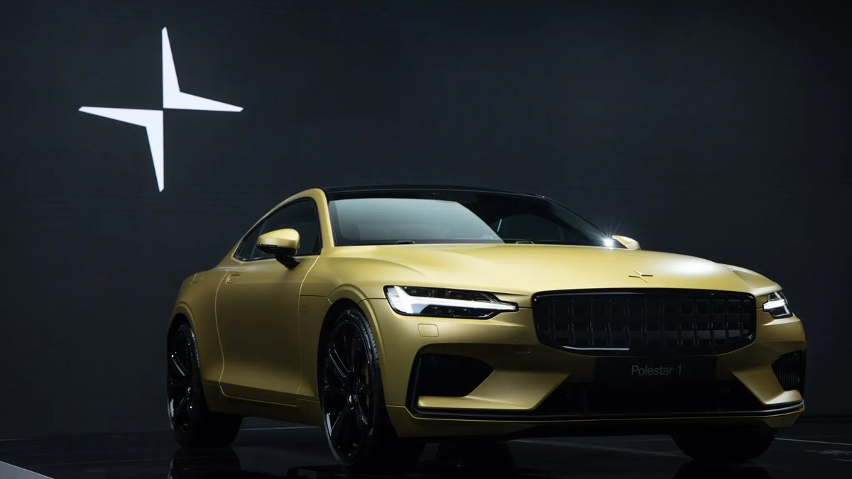 A striking yellow Polestar 1 sports car on display against a dark backdrop with the Polestar logo illuminated behind it.