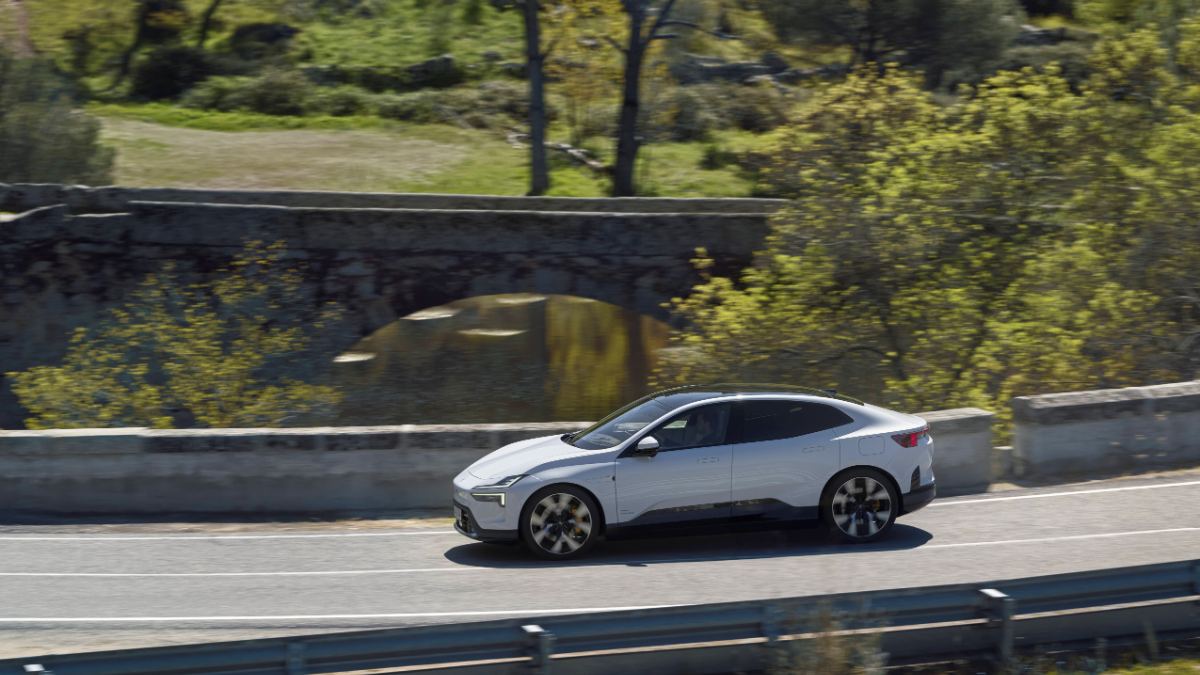 White 2025 Polestar 4 electric SUV driving on a winding road, aerodynamic side profile
