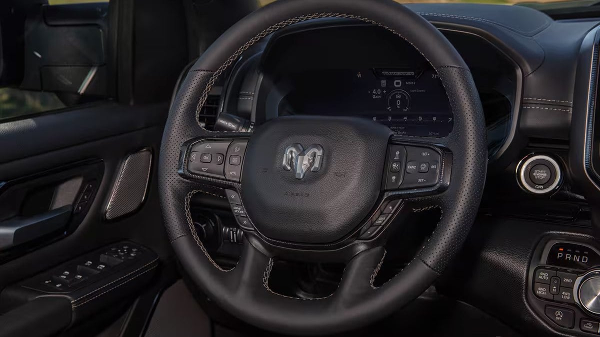 Close-up of a Ram steering wheel in a 2025 Ram 1500. The dashboard features a digital display and control buttons, exuding a sleek, high-tech feel.