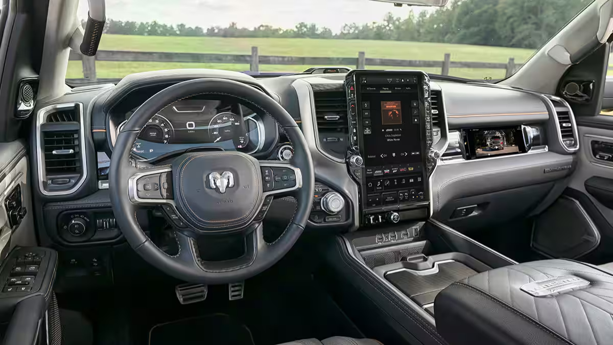 A 2025 Ram 1500 interior with a gray and black color scheme. Features a leather-wrapped steering wheel, large touchscreen display, and a scenic field view.