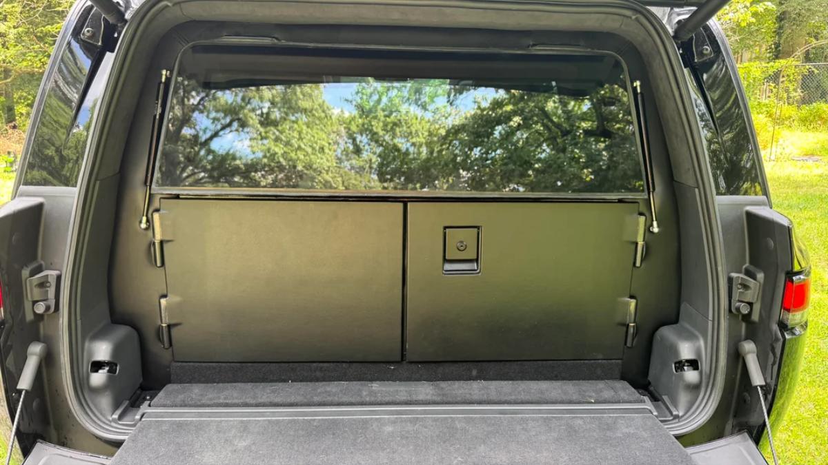View of the back interior of a vehicle showcasing a folded-down seat and spacious cargo area with a scenic backdrop.