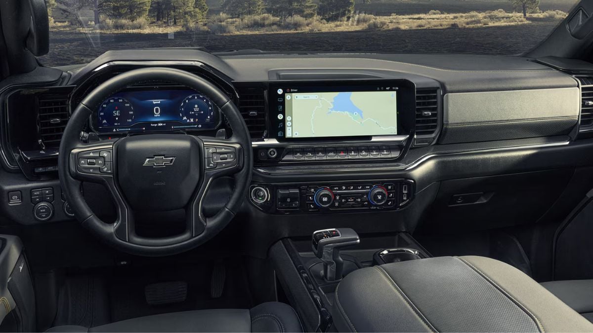 Silverado ZR2 interior featuring a Chevrolet steering wheel, digital dashboard, and large touchscreen displaying a map. Modern and sophisticated design.