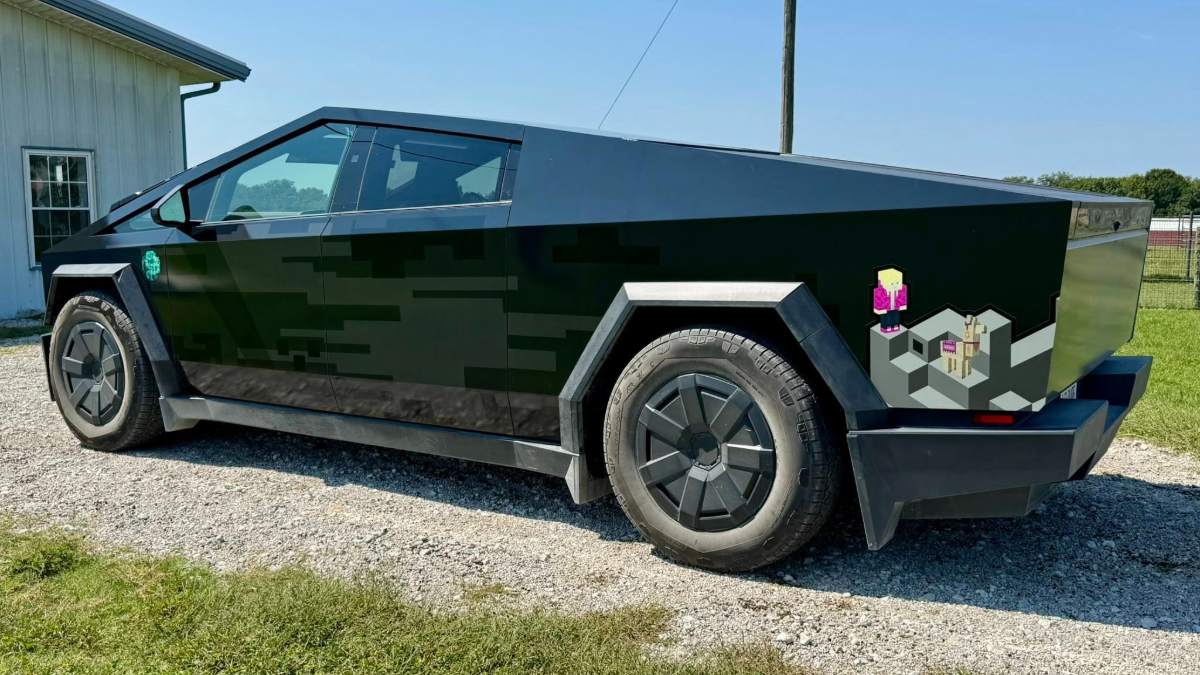 A black, angular vehicle parked on gravel with pixelated graphics on its side.