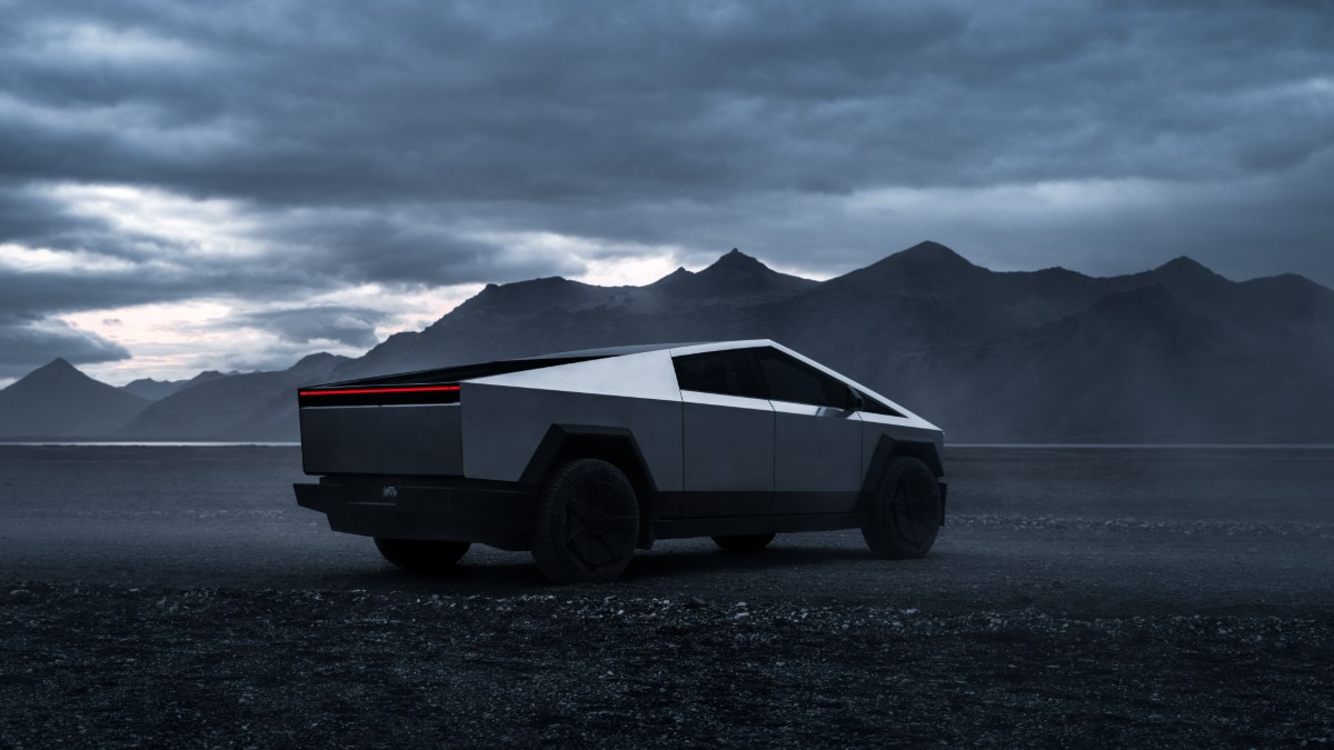 Tesla Cybertruck shown in a dramatic side profile view against a moody mountain landscape at dusk, highlighting its distinctive angular stainless steel exterior and illuminated light bar.