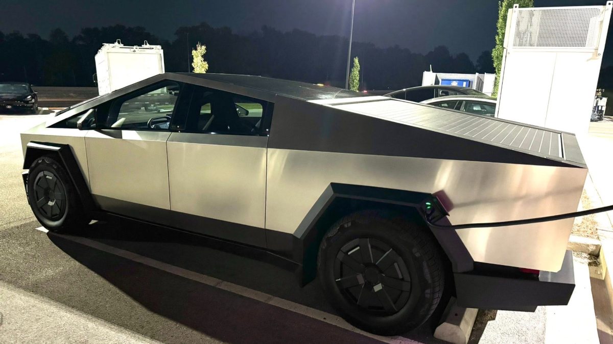 Tesla Cybertruck with angular stainless steel body parked at night in parking lot